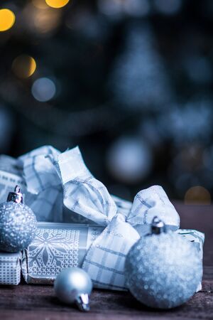 Christmas gifts in silver paper and silver bulbs on wood tableの写真素材