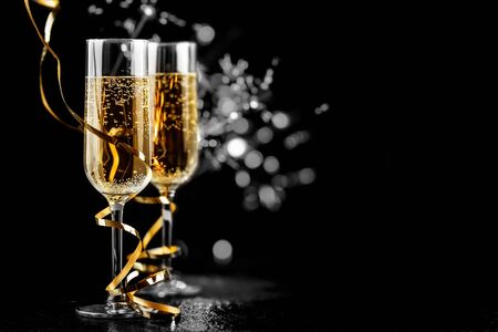 champagne glasses with golden ribbon and  sparkles on black background - new year celebrationの写真素材