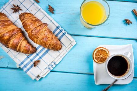 traditional french breakfast, crissant and coffee and juice on blue wood tableの写真素材