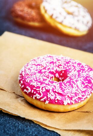 Chocolate, red, and white donuts and coffee on black stone tableの写真素材