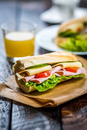 breakfast baguette with ham, cheese and lettuce on wood tableの写真素材