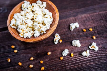 Popcorn in wood dish or bowl on dark wood tableの写真素材