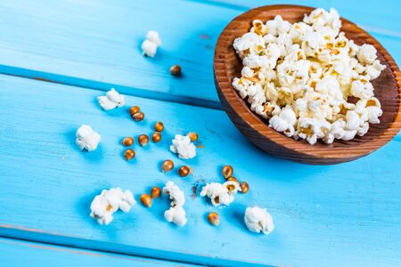Popcorn in wood dish or bowl on blue tableの写真素材