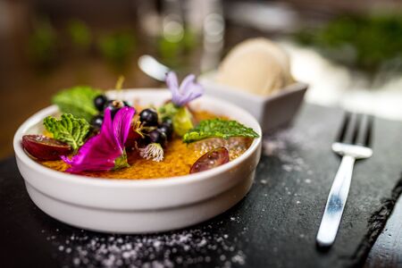 Traditional dessert Creme brulee with flowers in white bowlの写真素材