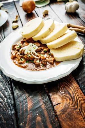 Traditional czech goulash with dumplings and beer on wooden tableの写真素材