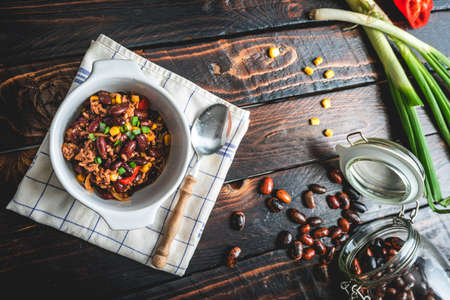 Mexican chili or chilli with meat. Cooked kidney bean, minced meat, chili, corn and pepper in pan on wood tableの写真素材
