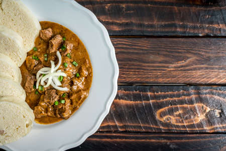 Traditional czech goulash with dumplings and beer on wooden tableの写真素材