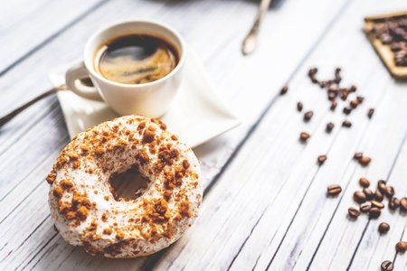 White donut with chocolate sprinkle and cup of coffee on wood tableの写真素材