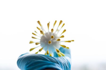 hand in a medical glove holds a model of the virusの写真素材