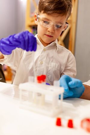 boy in laboratory gloves and goggles plays with laboratory test tubes and equipmentの写真素材