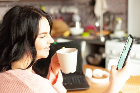 young woman works from home using her smartphone, concept of remote work, work on the Internet
