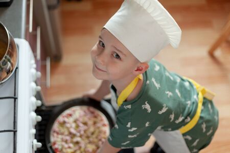 child cook preparing pizza in his kitchenの写真素材