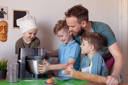 happy father with children cooks on paternity leave in the kitchenの写真素材
