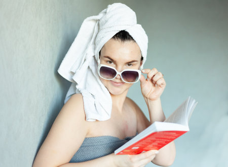 Sexy young beautiful naked girl in a towel with a bookの写真素材