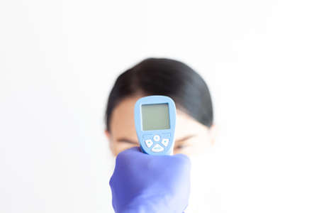 Doctor check woman body temperature using infrared thermometer for virus symptomの写真素材