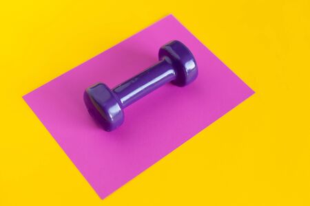 violet dumbbell on a pink background on a yellow backgroundの写真素材