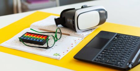 laptop, virtual reality glasses, copybook are on the table, desk of a modern schoolboy, concept of...