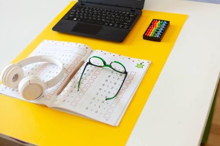 laptop, glasses, headphones, a notebook lie on the desk, desk of a modern schoolboy, concept of online school, education on the Internetの写真素材