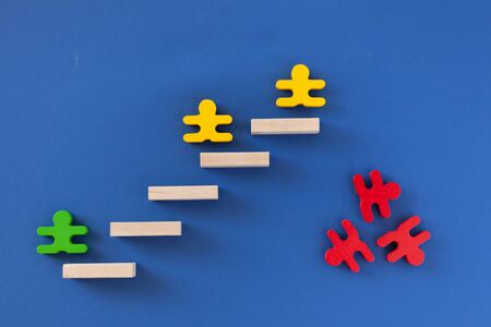 figures of men green yellow red climb the stairs and fall down, the concept of the social ladder, career growthの写真素材