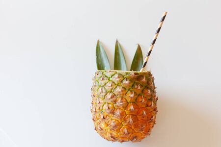 ripe pineapple fruit with a sliced top, cocktail roll, stylized green leaves, tropical bar conceptの写真素材