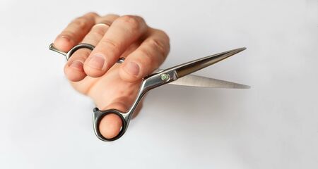 hand holds hairdressing scissors close-up, on a white light background, barbershop barber shop concept, hair care, hairdresser stylistの写真素材
