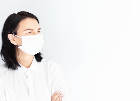 woman in medical mask on a white background, virus protection, doctor girl brunette in white clothesの写真素材