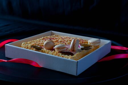 cake with macaroons with colored crumbs on a round black dish, on a dark background. Copy space. on a dark backgroundの写真素材