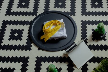kimono uniform white yellow belt neatly folded lie on a round black tray, near the tablet computer. rug black and white geometric rug, concept of online martial arts karate, taekwondoの写真素材