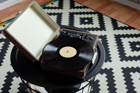 Vinyl player with plates on a black steel table. Entertainment 70s. Listen to music. Top view. Background black and white rug with geometric patterns of rhombusesの写真素材