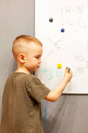 boy writes with marker on blackboard, pre-school classes, children's education, home trainingの写真素材