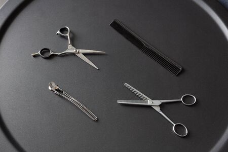 hairdresser tool scissors and comb on a black background, place for an inscriptionの写真素材