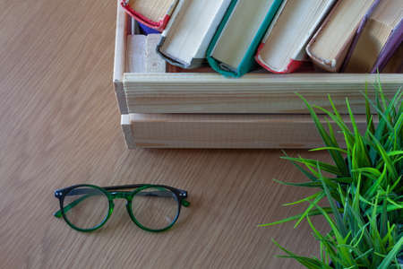 reading glasses and books in a wooden box on a wooden table, library