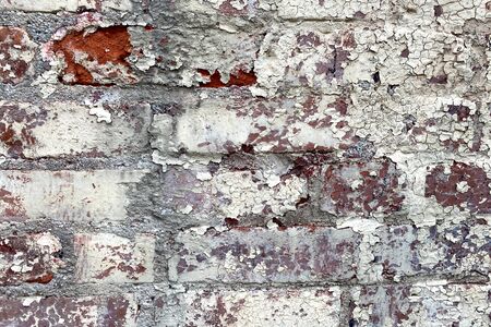 a vintage white pealing painted red brick wall