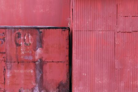 a rusty old red painted wall of abandoned metal building in a farm yard