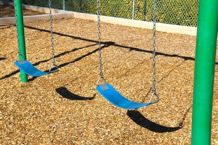 2 blue swings in a park playground