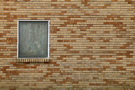 a single stained glass window on a colorful brick church wall