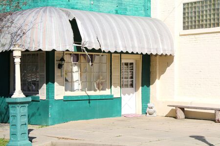 an abandoned green store building with awnings and glass brick window with shadowsの写真素材