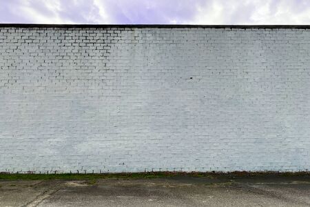 a white faded stone brick factory warehouse wall in an alleyの写真素材