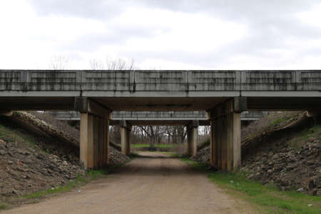 a concrete road bridge crossing over a country dirt trail