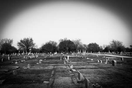 moody spooky graveyard cemetery with vignette photo effect and high contrast black and white filter as a halloween holiday sceneの写真素材