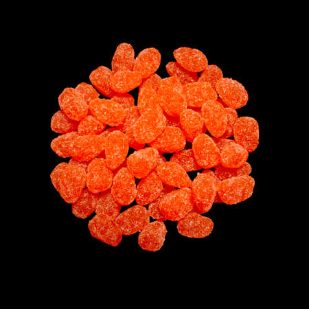 bright orange sugar coated jelly candy sweet treats in a round pile heap on black kitchen surfaceの写真素材