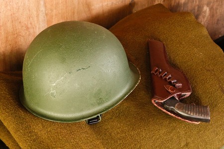 Military helmet and revolver on brown blanketの写真素材
