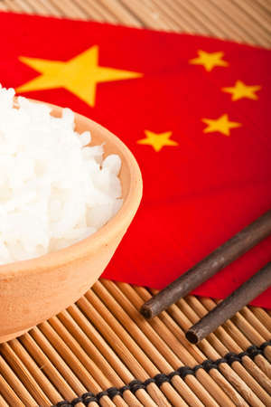 Rice bowl and chopsticks on chinese flag with bamboo mat (1)の写真素材