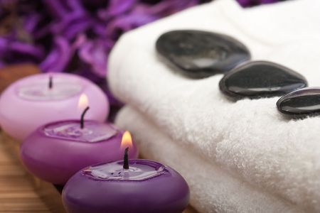 black hotstones on white towel with purple candles (1)の写真素材