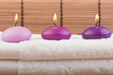 purple toned candles on white towel and bamboo background (1)の写真素材