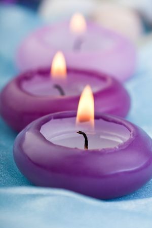 composition of three purple toned candles on baby blue silk (1)の写真素材