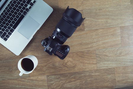 DSLR Camera with laptop on wooden tableの写真素材