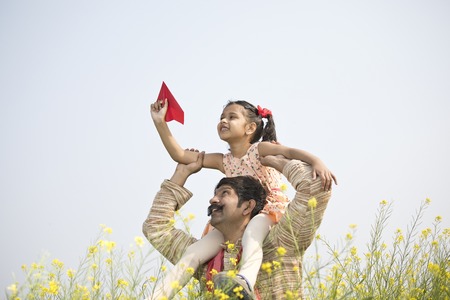 Girl sitting on fathers shoulder and throwing paper airplane