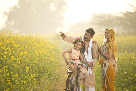 Rural Indian family with bicycle in agricultural fieldの写真素材