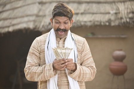 Excited farmer holding Indian rupee notes and screaming